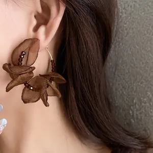 Close-up of brown fabric flower petal hoop earrings with crystal bead accents
