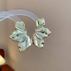 Detalle macro de pendientes de hoja dorada con textura y un acabado metálico brillante