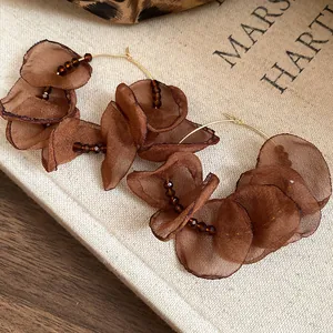 Detailed macro shot of brown organza fabric flower hoop earrings with beaded accents