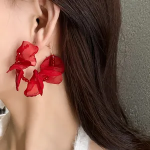 Close-up of elegant red fabric flower hoop earrings worn by an attractive model