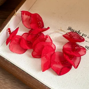 Close-up of layered red fabric petal hoop earrings with delicate red bead detailing.