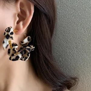 Close-up of stylish leopard print fabric flower hoop earrings worn on ear