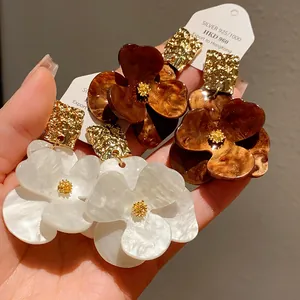 Detailed view of elegant flower-shaped earrings in white and tortoiseshell patterns.