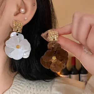 Detail view of large resin flower drop earrings with gold textured studs for women