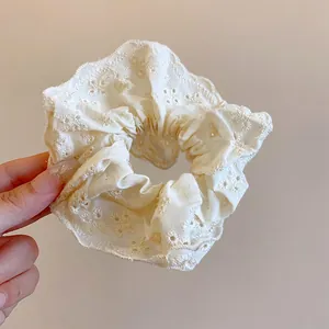 Close-up of white floral eyelet lace scrunchie with elegant ruffled texture
