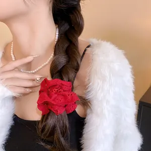 Detail shot of a red hollow lace flower scrunchie worn on a braided ponytail style