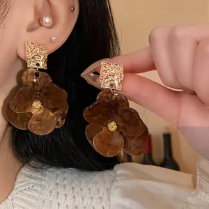 Exquisite macro detail of oversized resin flower earrings with textured gold square accents