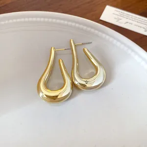 Primer plano de pendientes geométricos dorados en forma de U sobre un plato blanco
