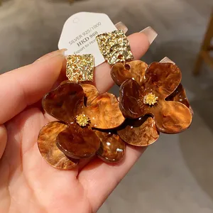 Detailed view of oversized brown marbled flower earrings with gold hammered studs