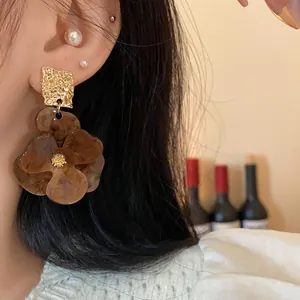 Close-up of statement brown tortoiseshell flower earrings with gold hammered square detail.