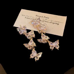 Macro detail of elegant gold-tone butterfly tassel earrings with sparkling zircons.