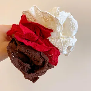 Close-up detail of three elegant lace floral scrunchies in cream, red and brown colors.