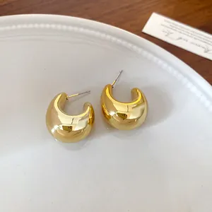 Primer plano detallado de elegantes pendientes geométricos dorados en forma de U