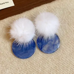 Detailed macro view of white fur ball and blue marble-textured resin round stud earrings