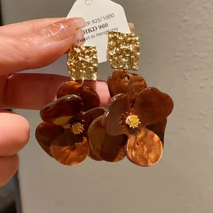 Close-up detail of vintage-style brown resin flower earrings with gold textured tops.
