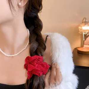 Detail of a red lace floral scrunchie on a braided hairstyle for an elegant look.
