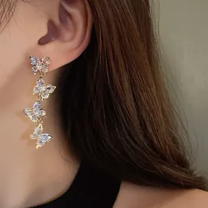 Close-up of silver needle zircon butterfly tassel earrings worn by a model.