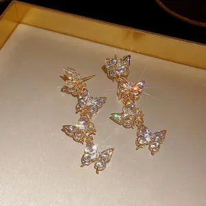 Detailed macro view of sparkling zircon butterfly tassel earrings in a gold setting