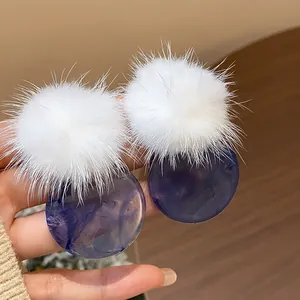 Detail view of stylish white fur pom-pom and blue marble resin round stud earrings
