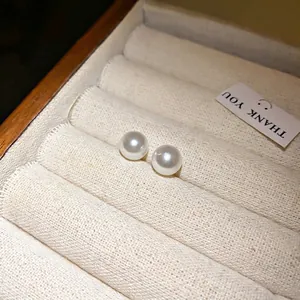 Elegantes pendientes de perlas blancas de estilo francés con agujas de plata en caja.