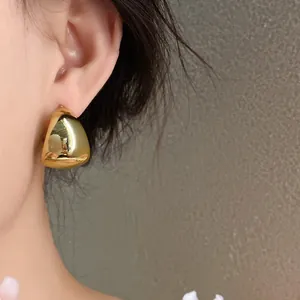 Primer plano de un elegante pendiente dorado geométrico en forma de U usado por una modelo