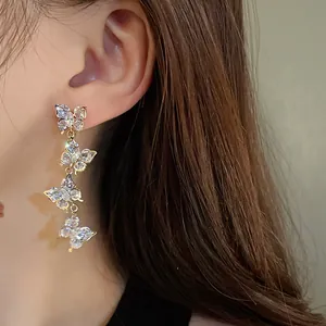 Macro view of sparkling zircon butterfly tassel drop earrings worn on a model's ear
