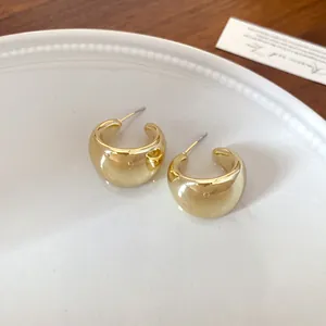 Elegantes pendientes geométricos dorados en forma de U sobre un plato de cerámica