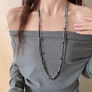 Elegante collana a più strati con perle di vetro nere e catene d'argento su modella