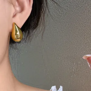 Primer plano de pendiente de botón minimalista de gota dorada, estilo de lujo elegante