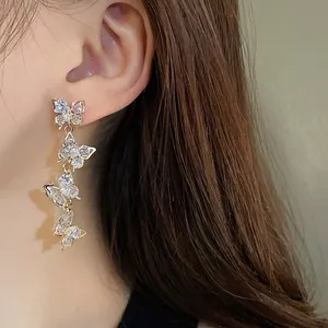 Detail view of elegant sparkly zirconia butterfly tassel drop earrings worn on a female ear