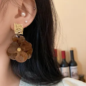Close-up of stylish brown tortoiseshell flower earrings with gold hammered finish top.