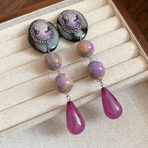 Vintage cameo earrings with purple resin beads and teardrop pendants in display box.