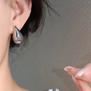 Primer plano de un pendiente de gota plateado en la oreja de una modelo