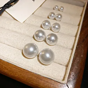 Vista detallada de pendientes de perlas de tamaños graduados en un joyero de madera