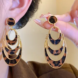 Close-up detail of leopard print hollow oval earrings with gold-toned plating finish