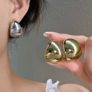 Detalle de pendientes de gota geométricos en color oro y plata con acabado brillante