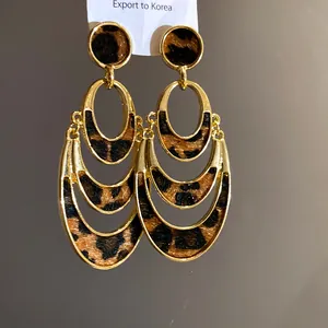 Close-up of gold-plated oval dangle earrings with leopard print texture details