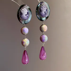 Detailed macro view showing the fine craft of vintage purple cameo drop earrings.