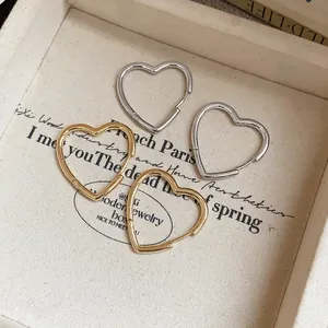 Detailed view of elegant minimalist gold and silver heart-shaped hoop earrings in a tray