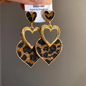 Close-up of leopard print heart-shaped earrings with gold-toned metal hollow design