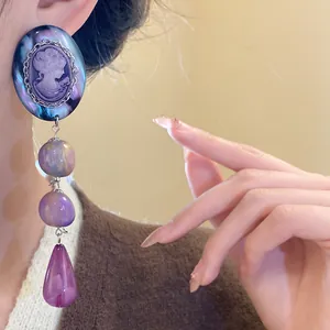 Detailed view of a vintage cameo drop earring featuring purple teardrop tassel and pearls