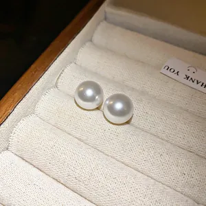 Primer plano de pendientes de botón de perlas blancas minimalistas en joyero vintage