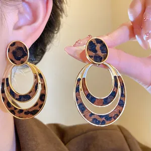 Close-up detail showing the texture of leopard print oval hollow earrings with gold finish
