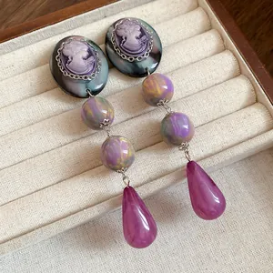 Detailed macro view of vintage cameo resin drop earrings with purple marble beads and drops