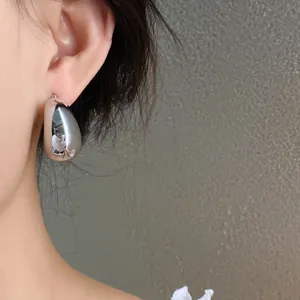 Primer plano de un pendiente de gota plateado minimalista con un acabado metálico pulido