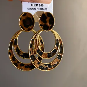 Detail shot of gold triple-hoop earrings with textured leopard print inlay on white card