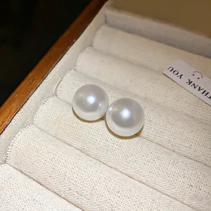 Primer plano detallado de elegantes pendientes de perlas blancas en bandeja de terciopelo