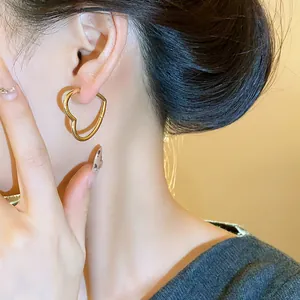 Elegant close-up view of a minimalist heart-shaped gold earring worn on the ear of a model