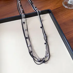 Elegante collana a più strati con catene nere e argento e dettagli in perle di vetro.