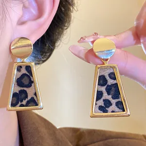 Close-up showing the leopard print texture and gold finish of these stylish drop earrings.